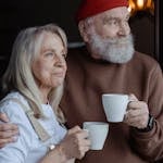 A senior couple embraces while enjoying coffee, symbolizing love and companionship.