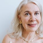 A smiling senior woman with earrings and necklace from a portrait session.