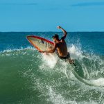 A surfer skillfully riding a wave with a surfboard, showcasing dynamic motion and excitement.