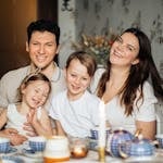 Cheerful family of four enjoying a warm and cozy teatime at home, surrounded by love and laughter.