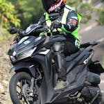 Motorcyclist wearing helmet and gear rides on a winding road.
